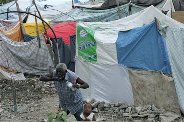 A man brushes his teeth next to a boy at a camp for homeless earthquake survivors at the Pele neighborhood in Port-au-Prince, Friday, Feb. 26, 2010. A magnitude-7 earthquake hit Haiti last Jan. 12. (AP Photo/Eraldo Peres)
